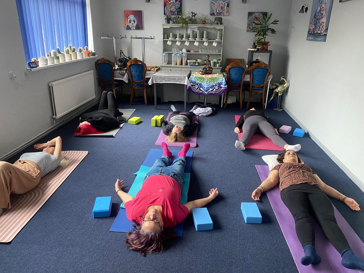 A workplace yoga session — staff resting on mats with blocks in their office space