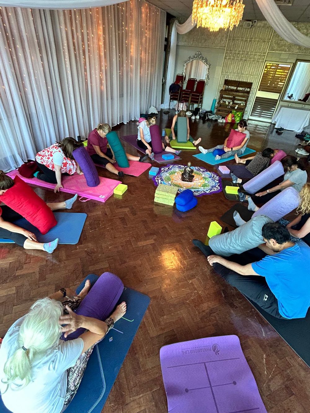 A retreat circle from above — colourful mats and cushions around a mandala
