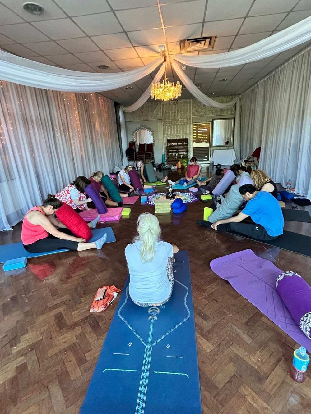 A retreat hall glowing under a canopy of fairy lights, mats laid out in a circle